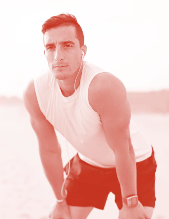 Man in a white tank top and red shorts posing outdoors