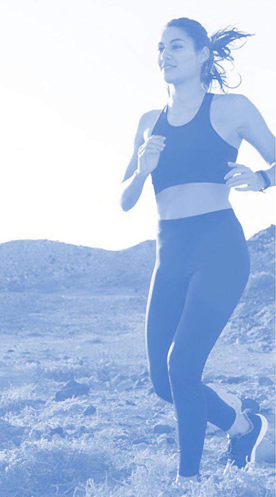 Woman running on a mountain trail with a blue filter applied