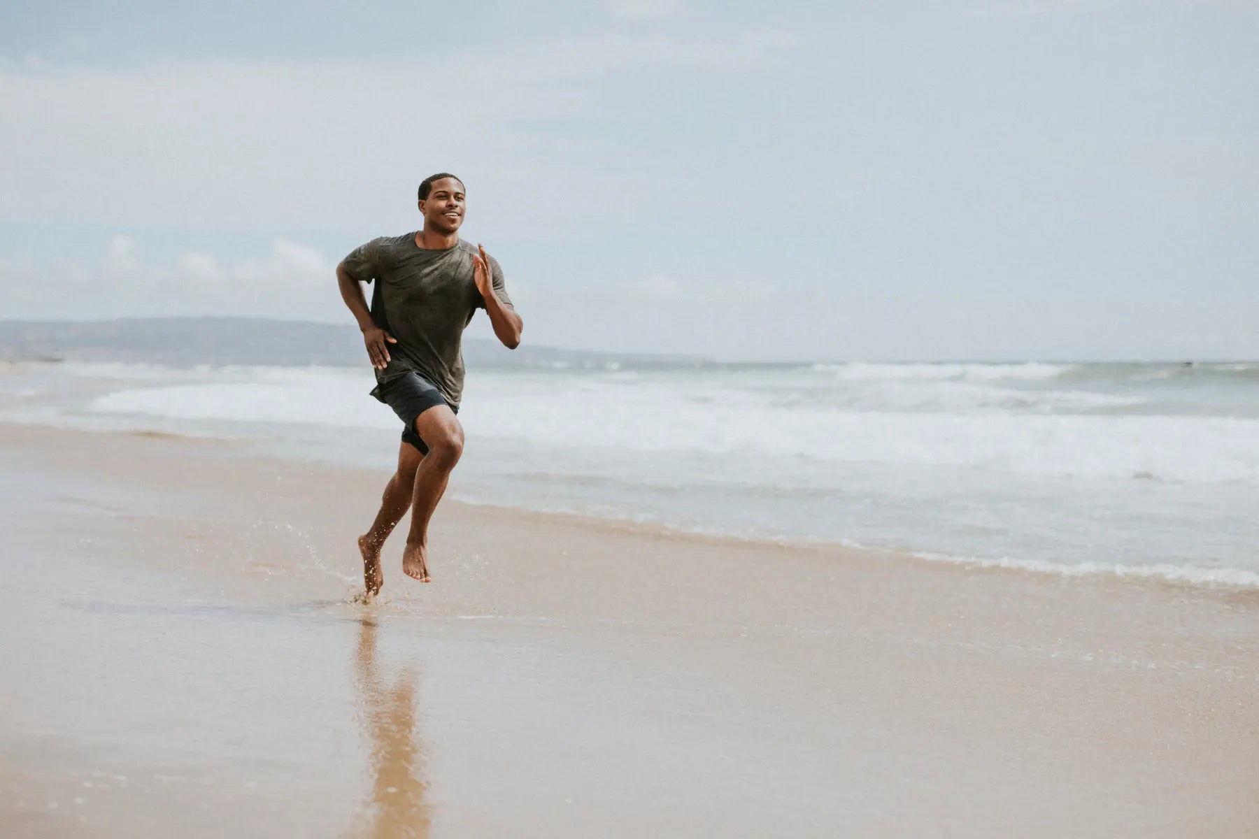 Bone density analysis supported by an athletic man running barefoot on the beach, demonstrating strength and skeletal health.