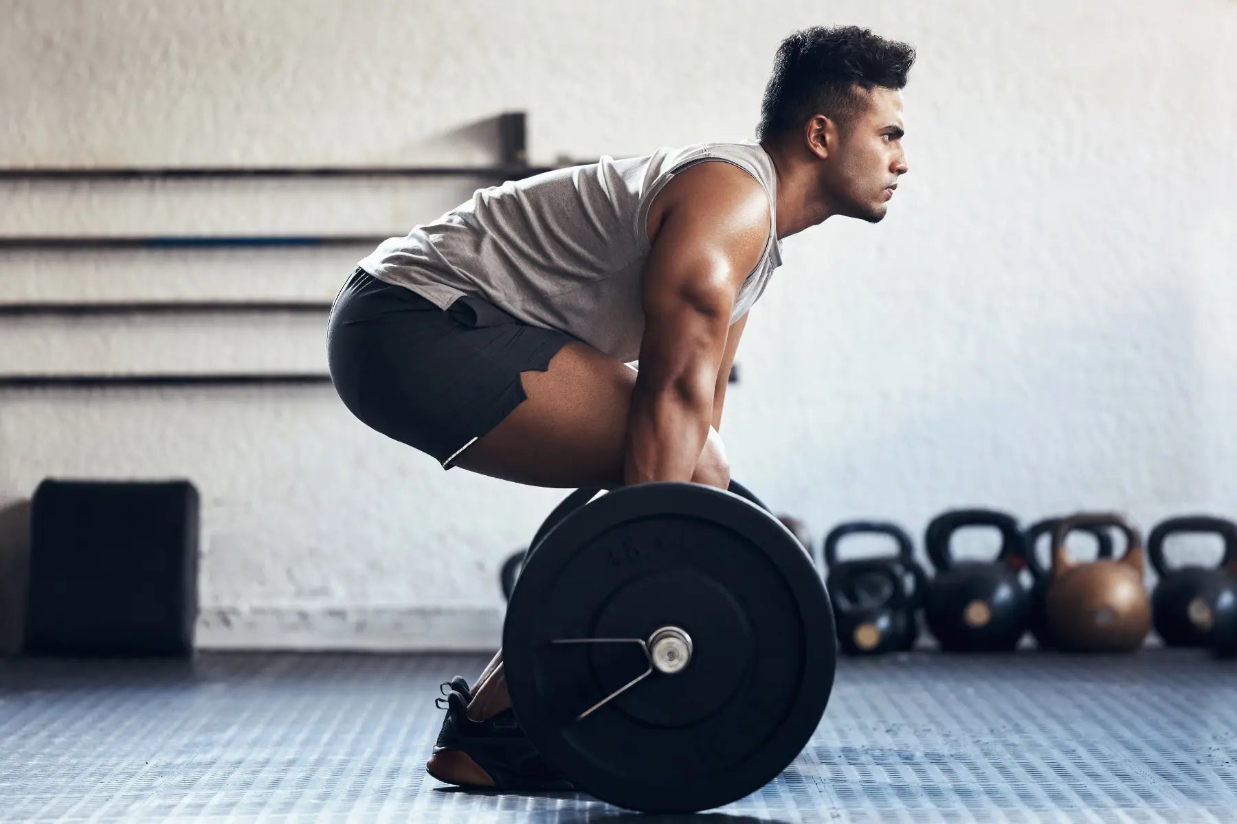DEXA scan eligibility supported by man lifting barbell to improve strength and monitor bone density.