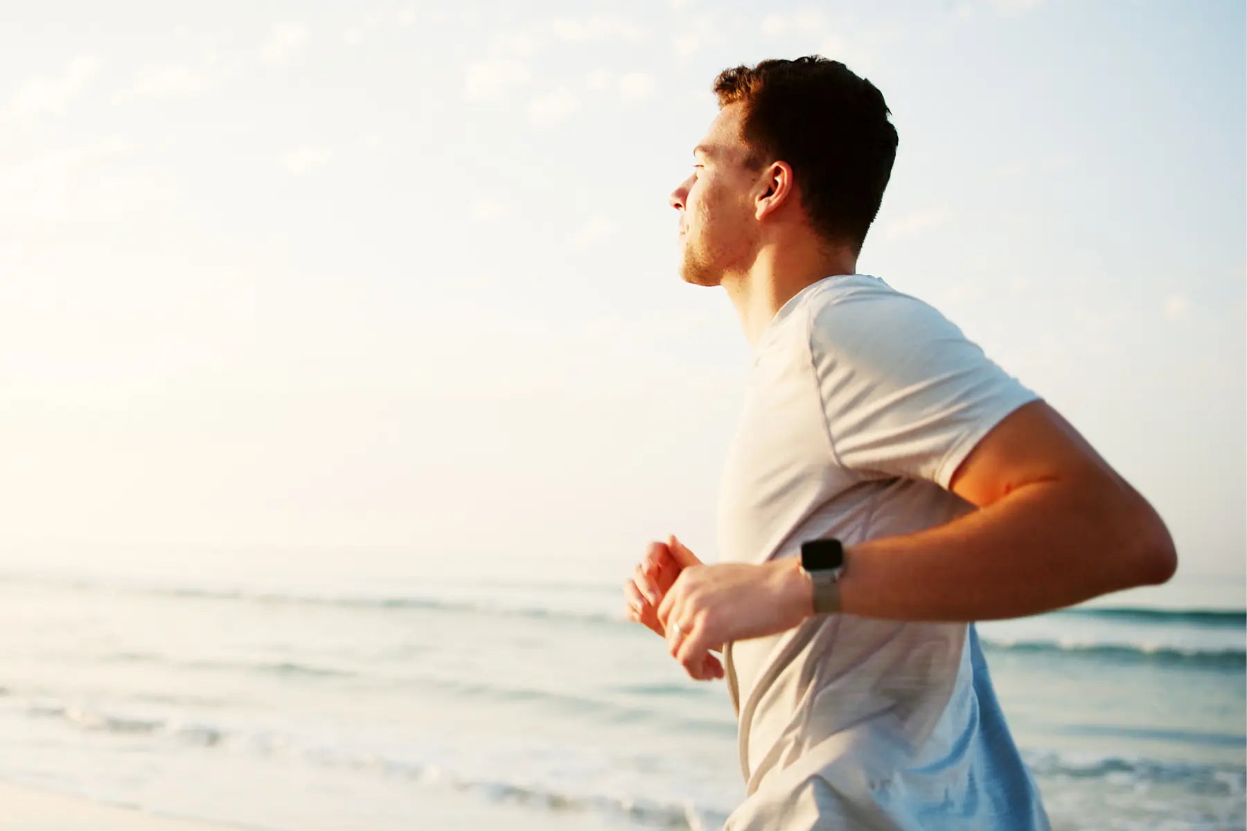 DEXA scan for fat tracking supported by man running along the beach to maintain body composition and health.