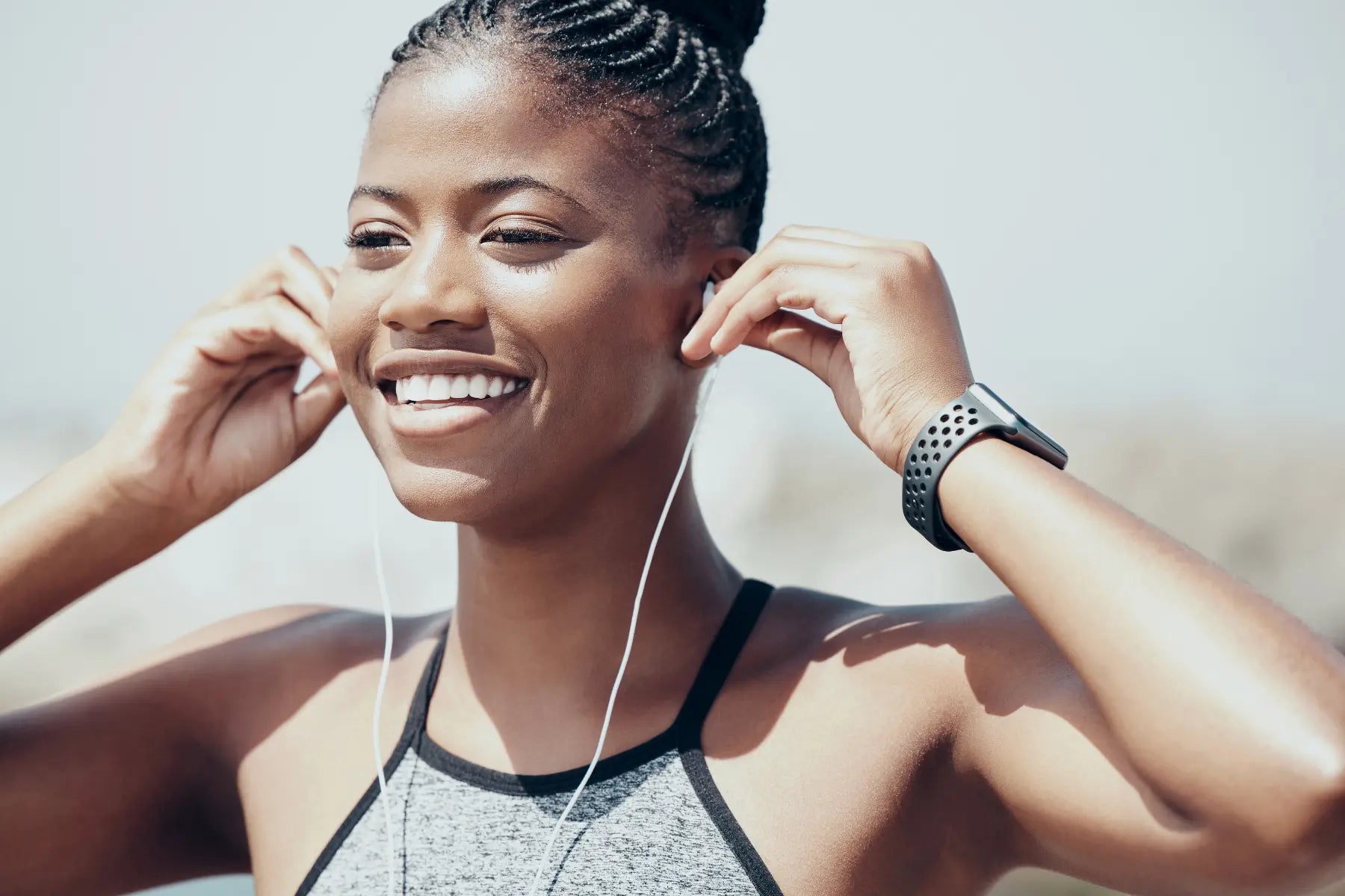 Decrease visceral fat motivation as smiling woman prepares for workout wearing smartwatch and putting in earphones.