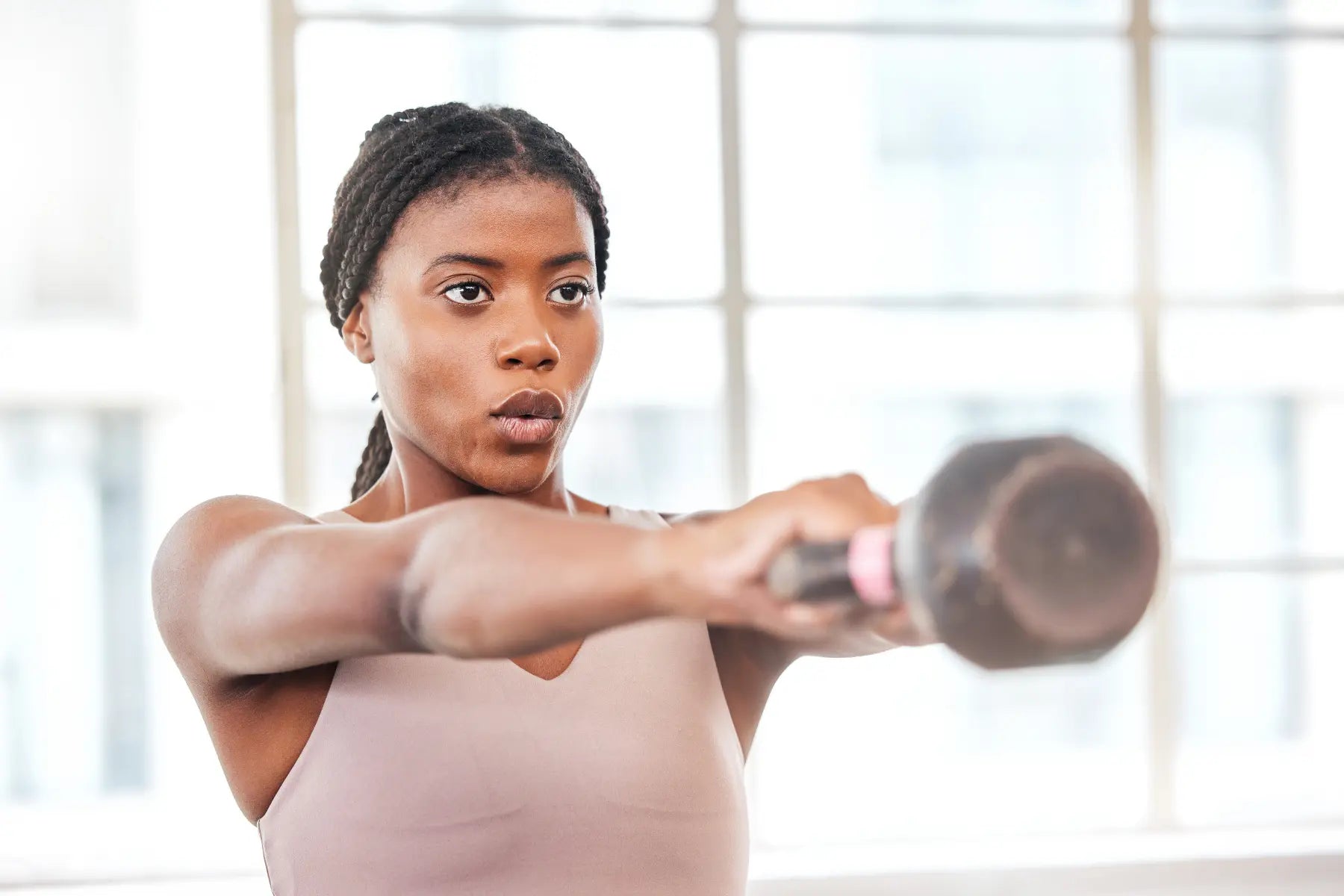 GLP-1 weight loss monitoring shown through a focused woman lifting a kettlebell during an indoor workout.