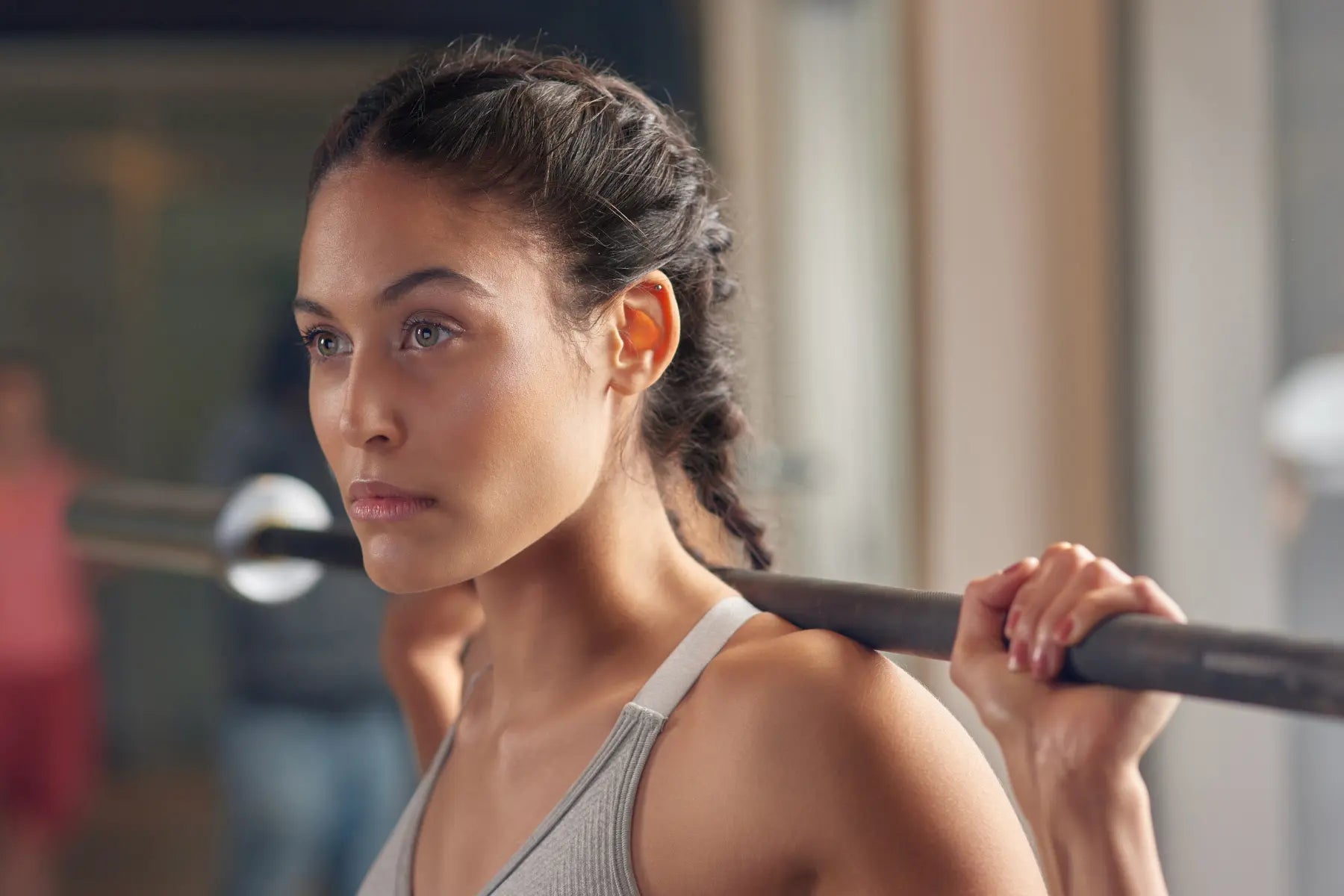 Strength training session with a focused woman resting a barbell across her shoulders in a gym.