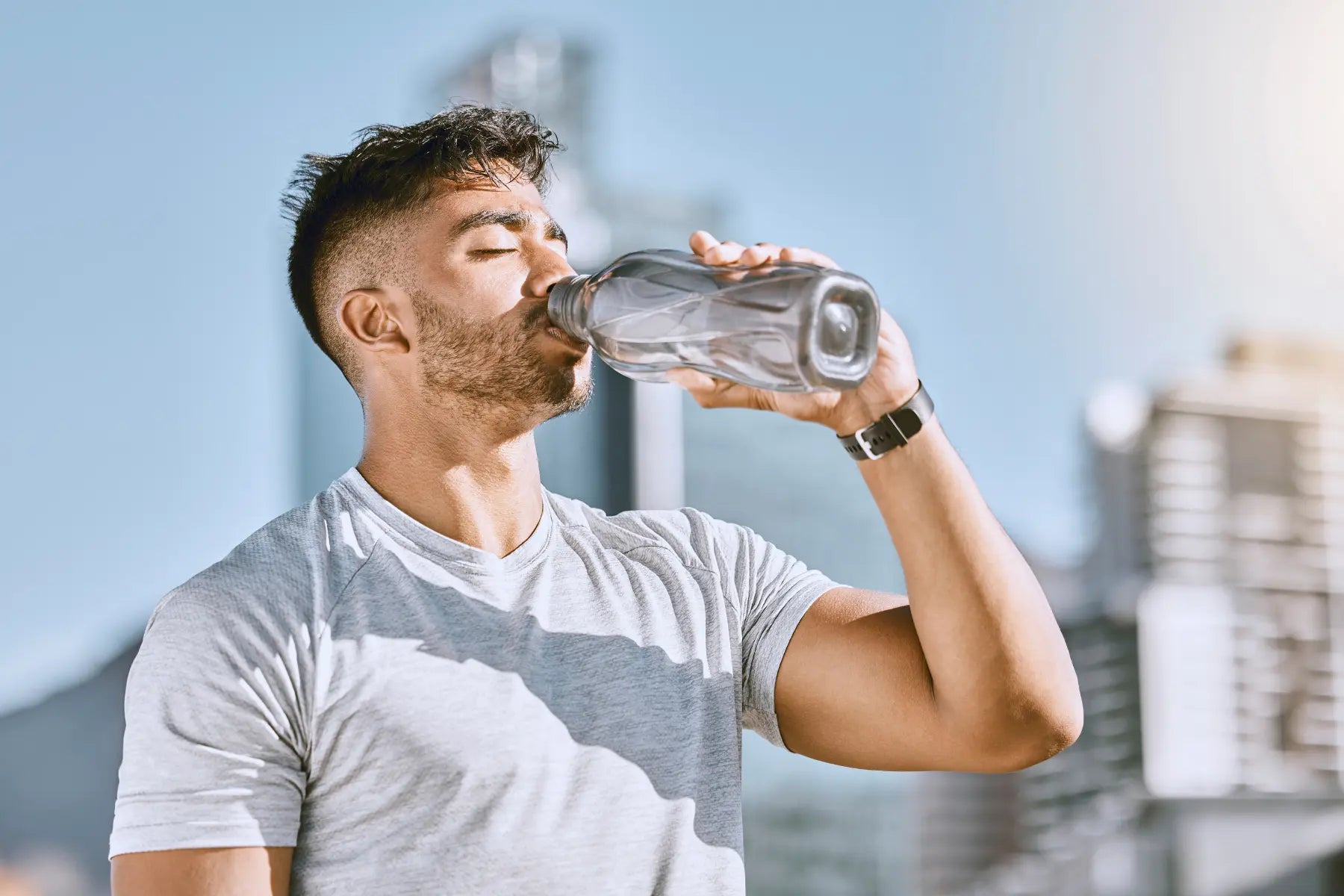 Best GLP-1 for weight loss shown by fit man drinking water after outdoor workout in city environment.