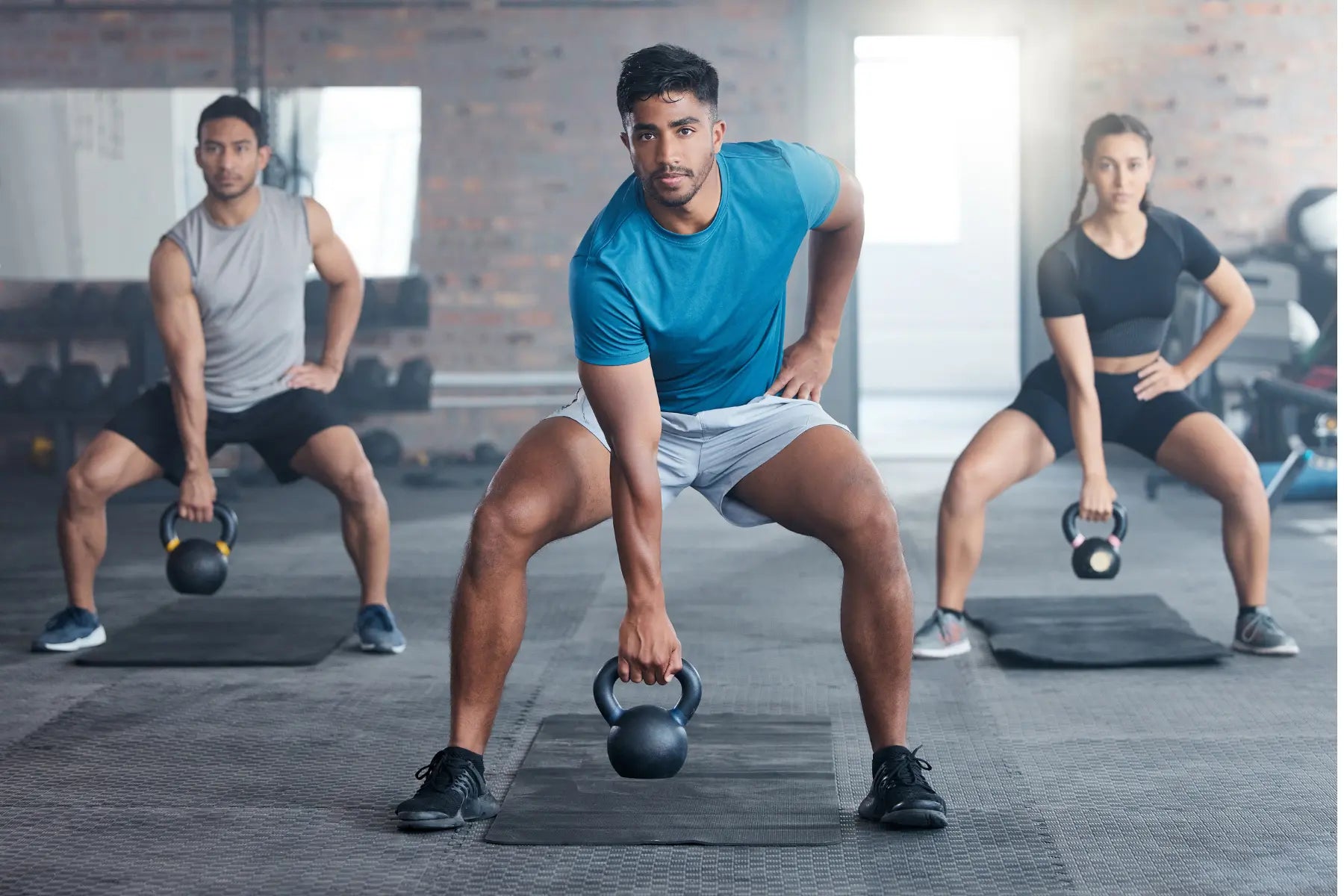 Body composition scan training session with focused group lifting kettlebells during indoor strength workout.