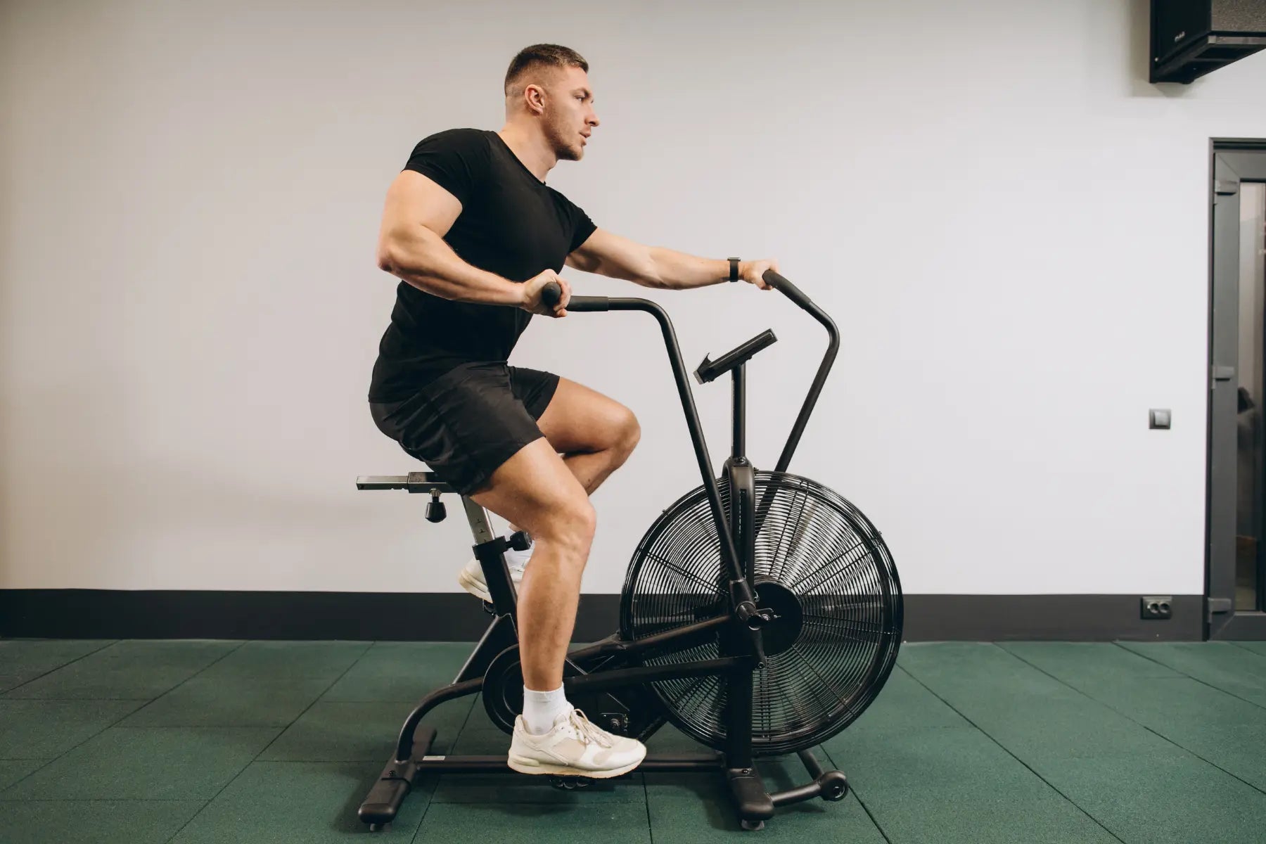 Bone density improved through exercise as a man trains on a stationary air bike in the gym.