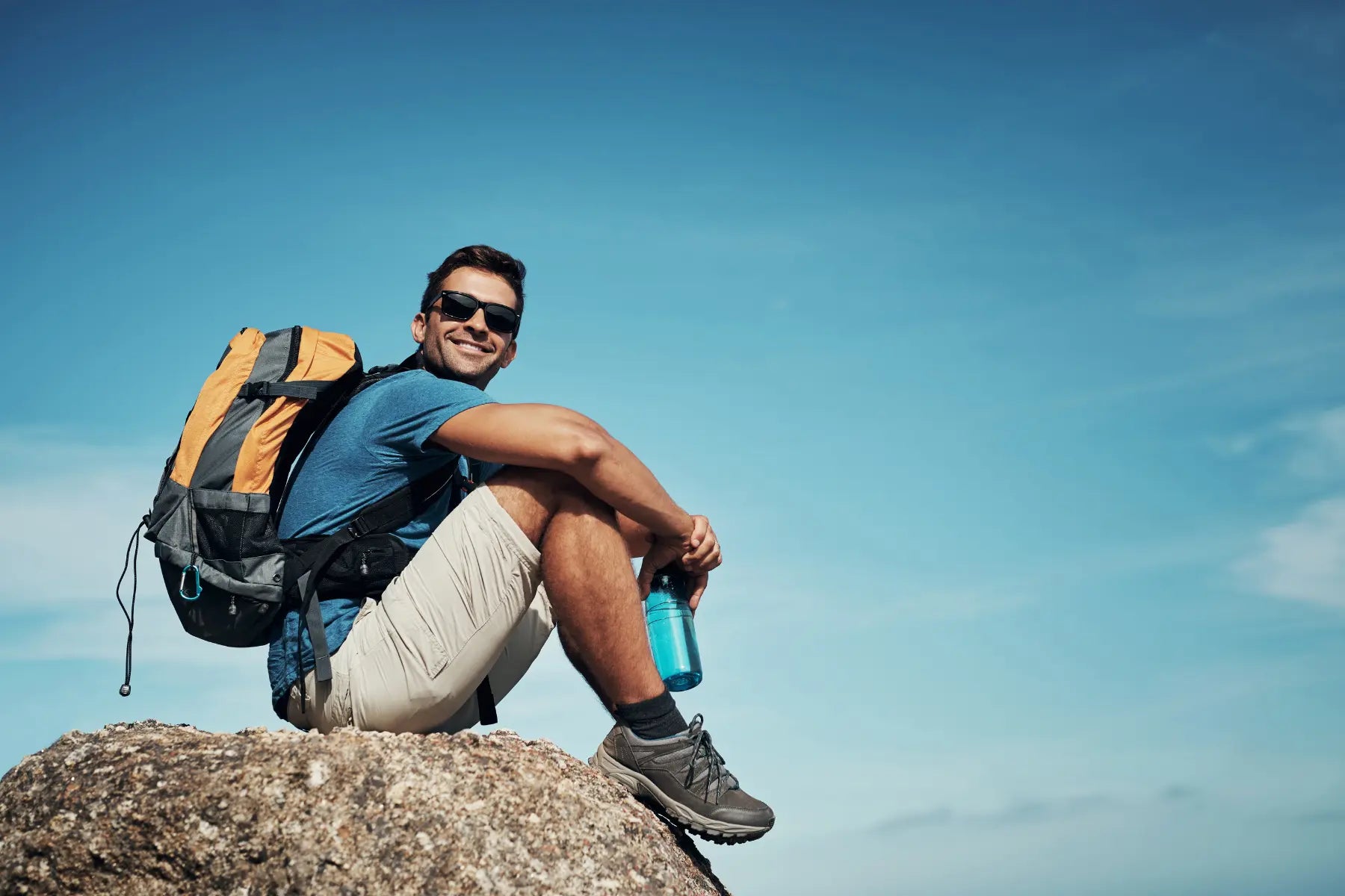 Bone health supported by a smiling hiker sitting on a rock with a backpack and water bottle