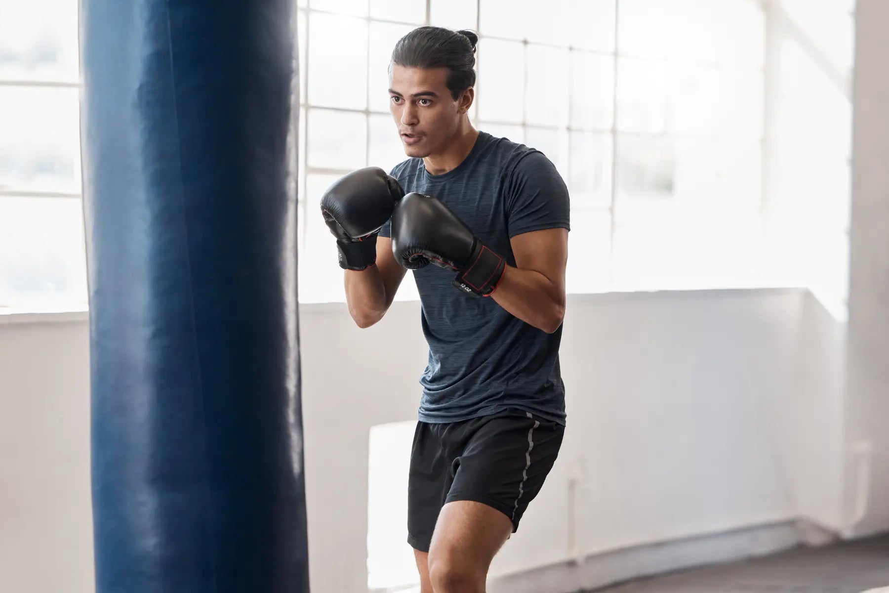 Building lean muscle with boxing training as a man practices punches on a heavy bag in the gym.