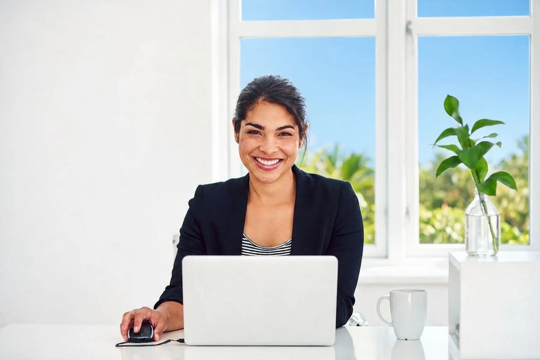 Cognitive function on display as a focused woman smiles while working at her laptop in a bright office.