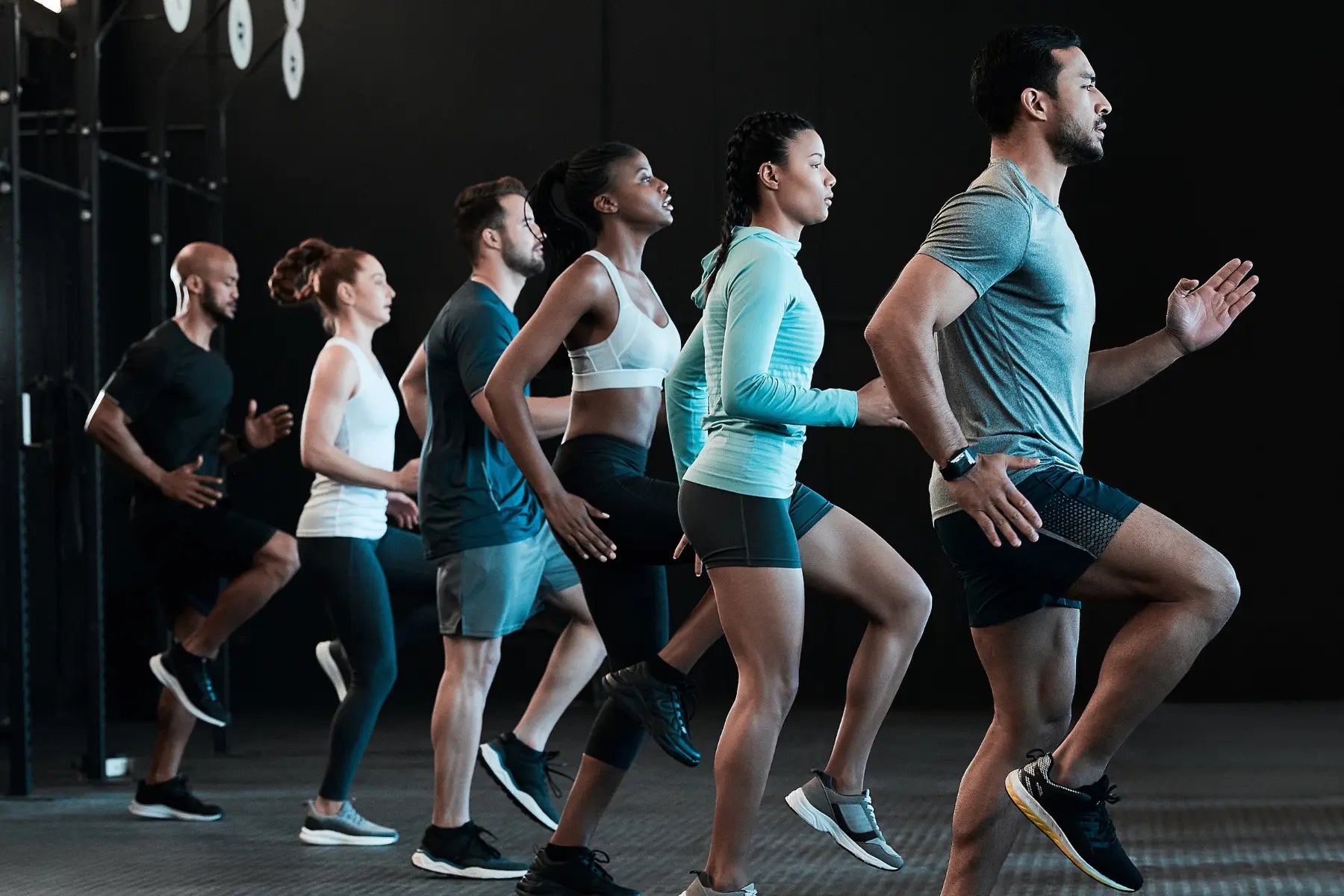 Group of adults in activewear running in formation during a group workout focused on health optimization.