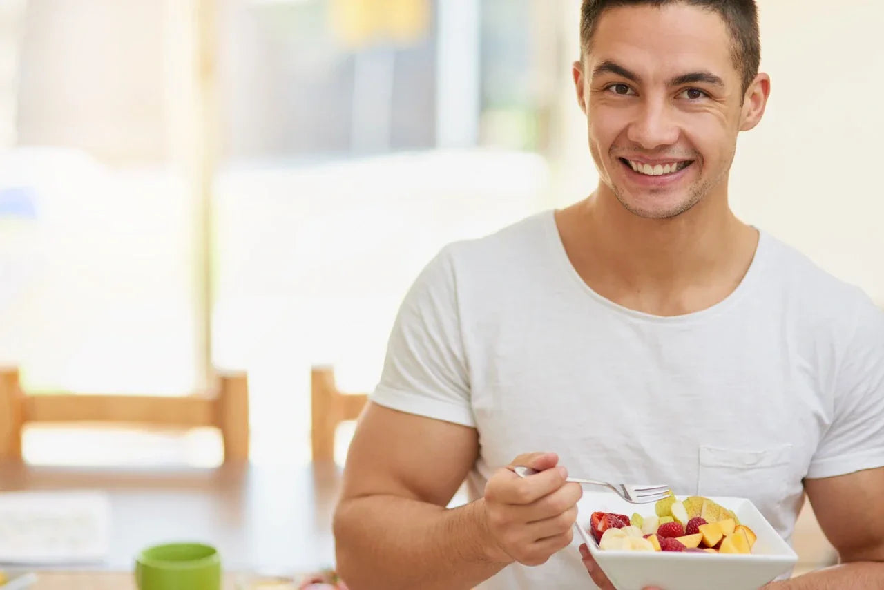 Healthy man eating fresh fruit salad, supporting gut health and digestion for accurate microbiome testing results.