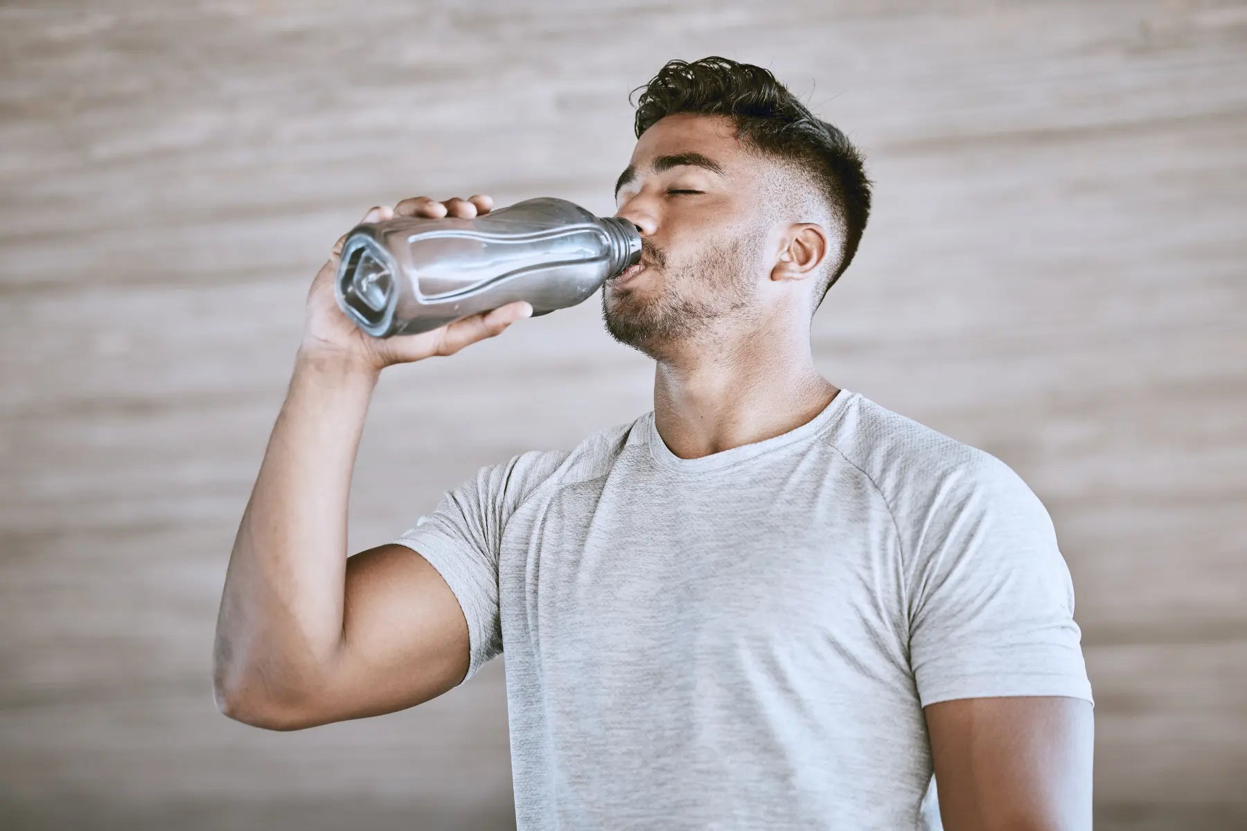 Ozempic and weight loss concept with a fit man drinking water after exercise in a health-focused setting.