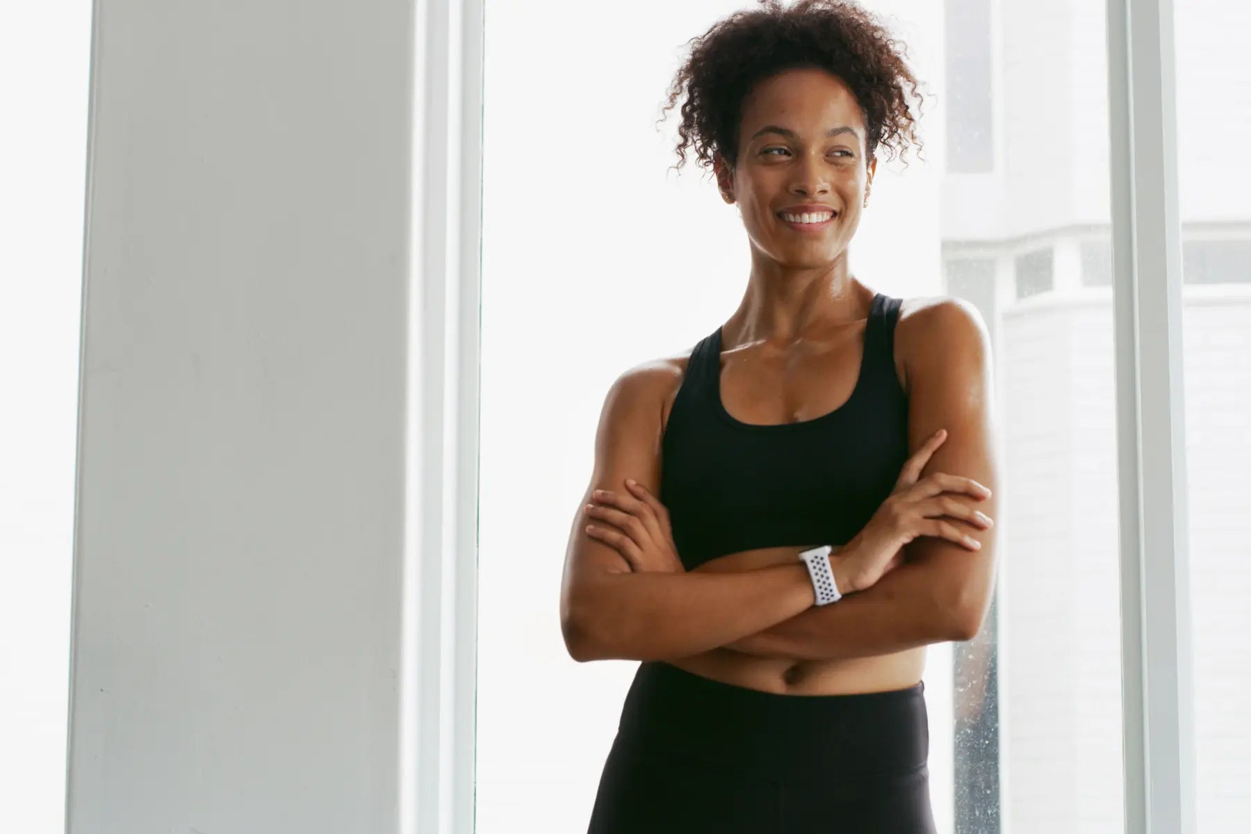 Sustainable weight loss success shown by fit woman in workout gear smiling confidently after exercise.