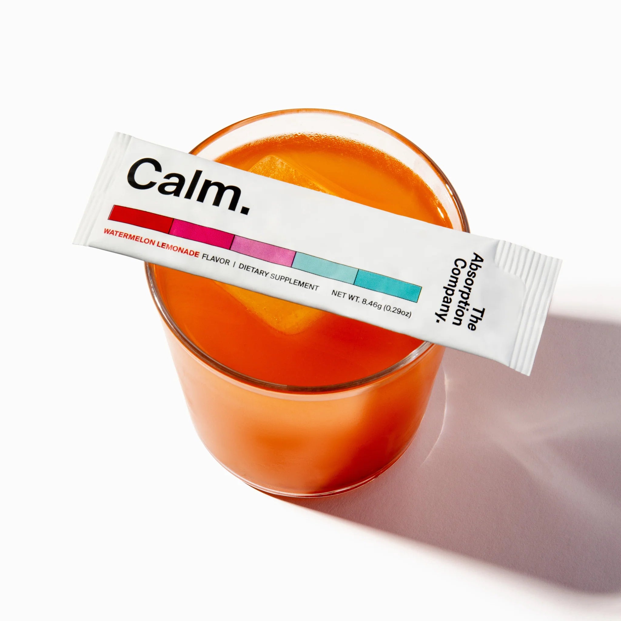 Calm supplement packet on a glass of orange juice with a white background