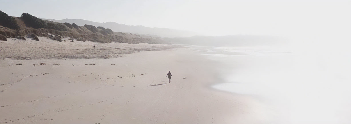 Video of a BOD customer running alone on a misty beach with rocks in the distance.