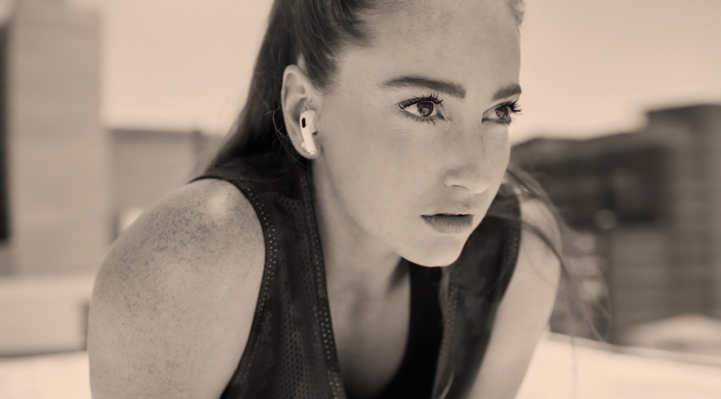 Woman wearing earbuds with a blurred indoor background